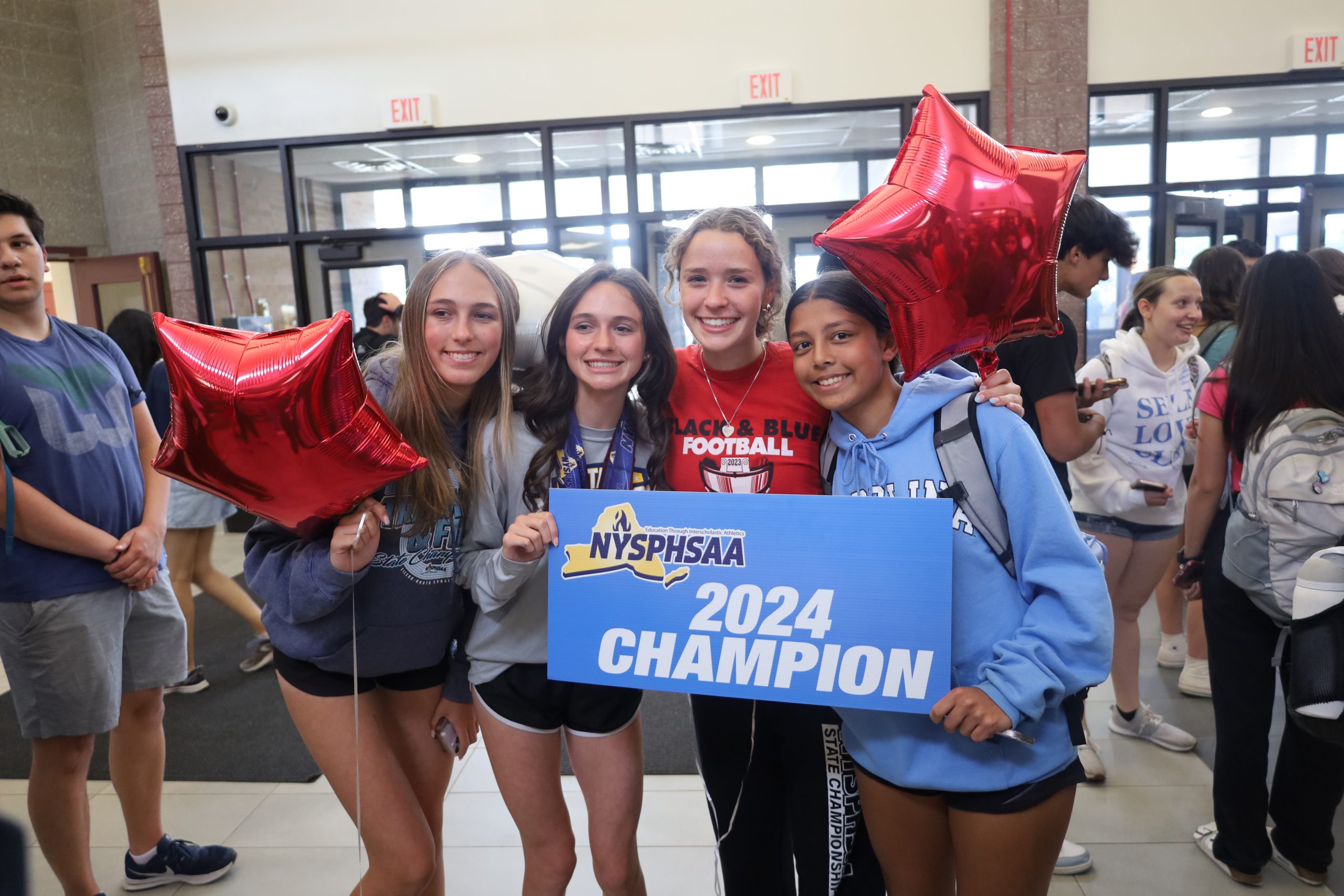 Four track and field athletes poses together. They are holding a sign that reads NYSPHSAA 2024 Champion