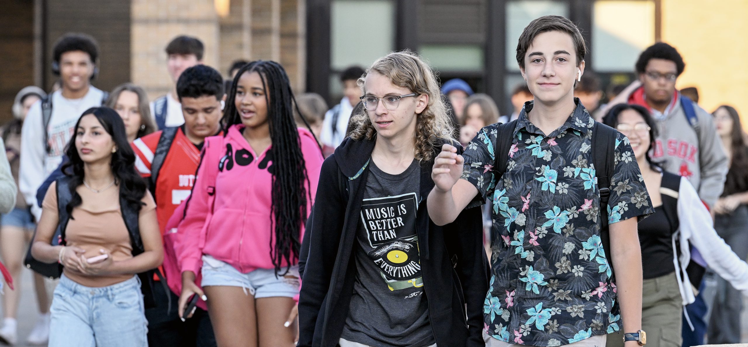 GHS students on the first day of school. They are walking into the building. One student is smiling at the camera.