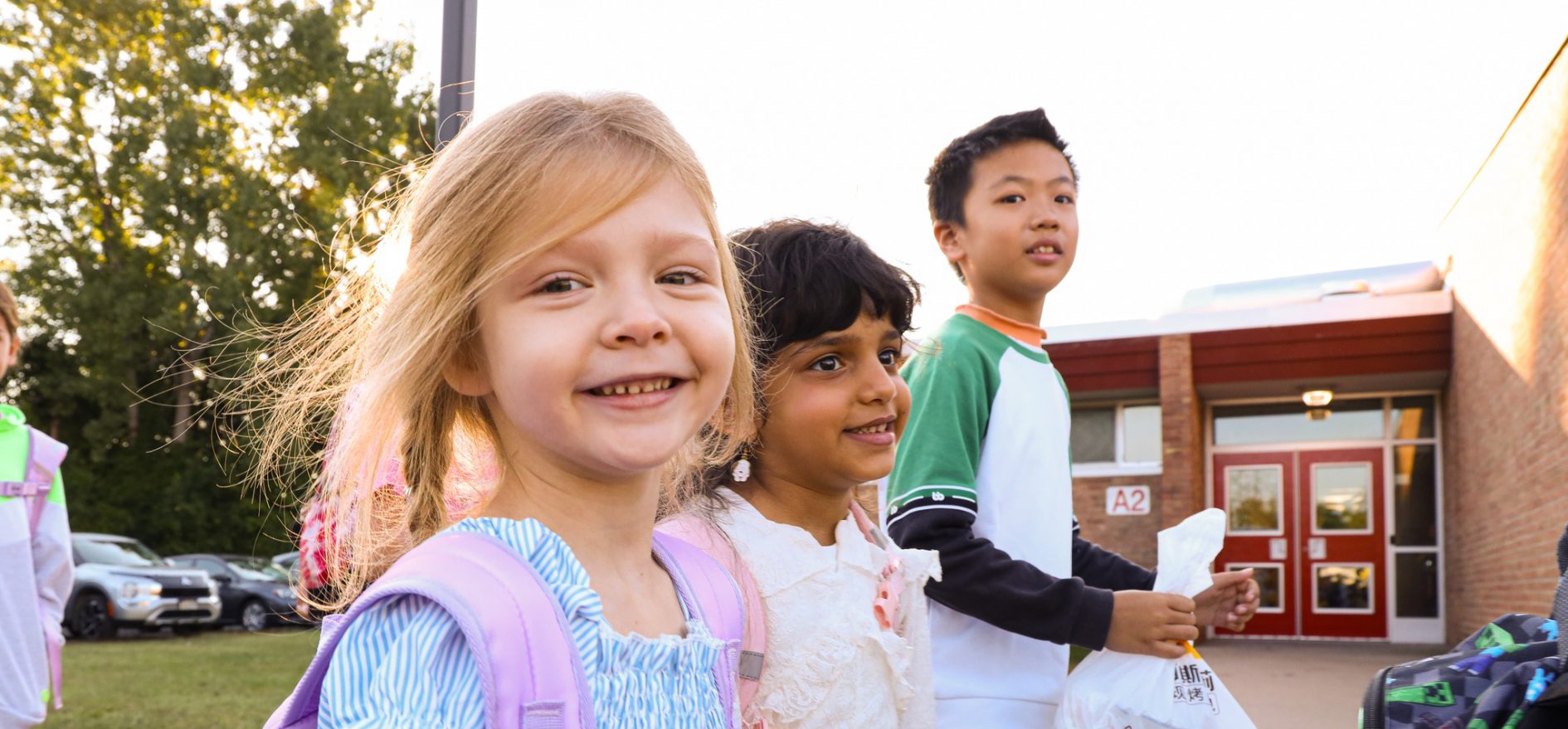 Elementary school students smiling on their first day of school.