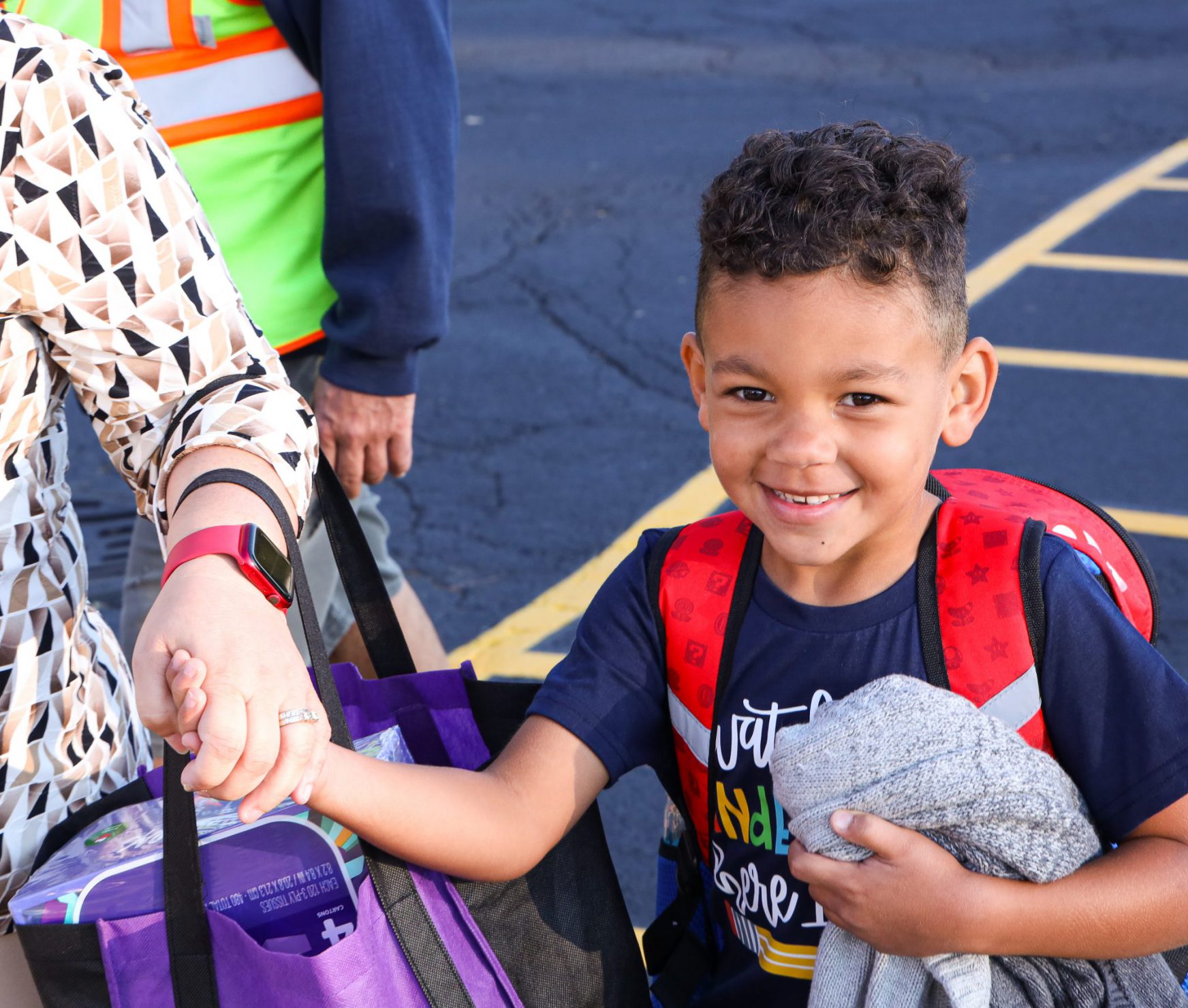 Student smiling while walking with parent on the first day of school.