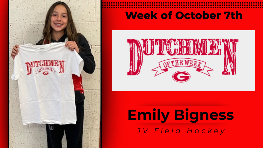 Student smiling and holding a Dutchmen of the Week shirt up for a photo. 