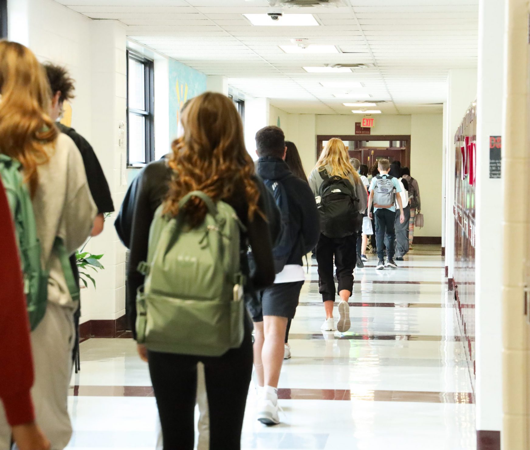 Students walking down the halls wearing their backpacks at the end of the day.