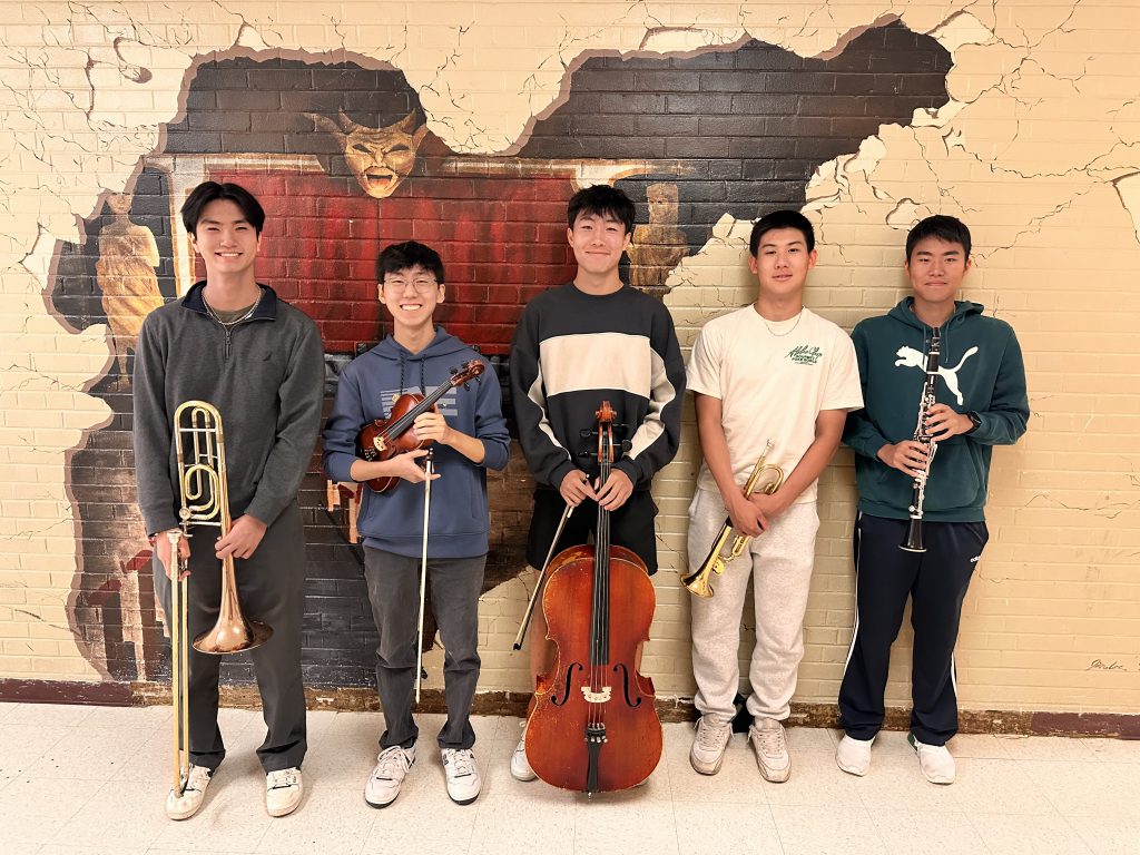 Five students holding instruments and being recognized for musical excellence