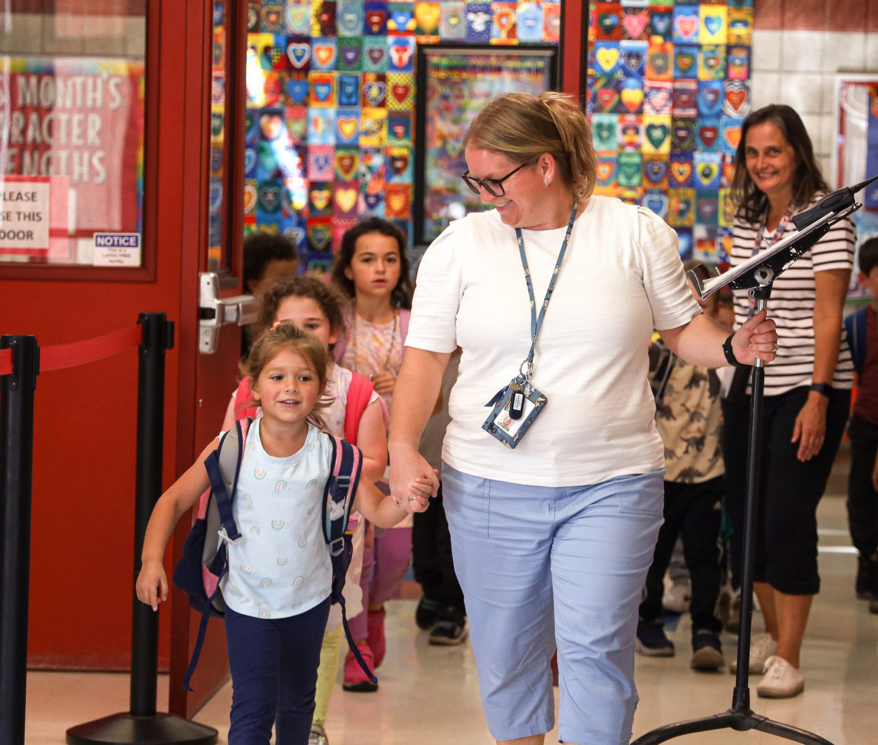 Staff member holding hands with student and smiling.