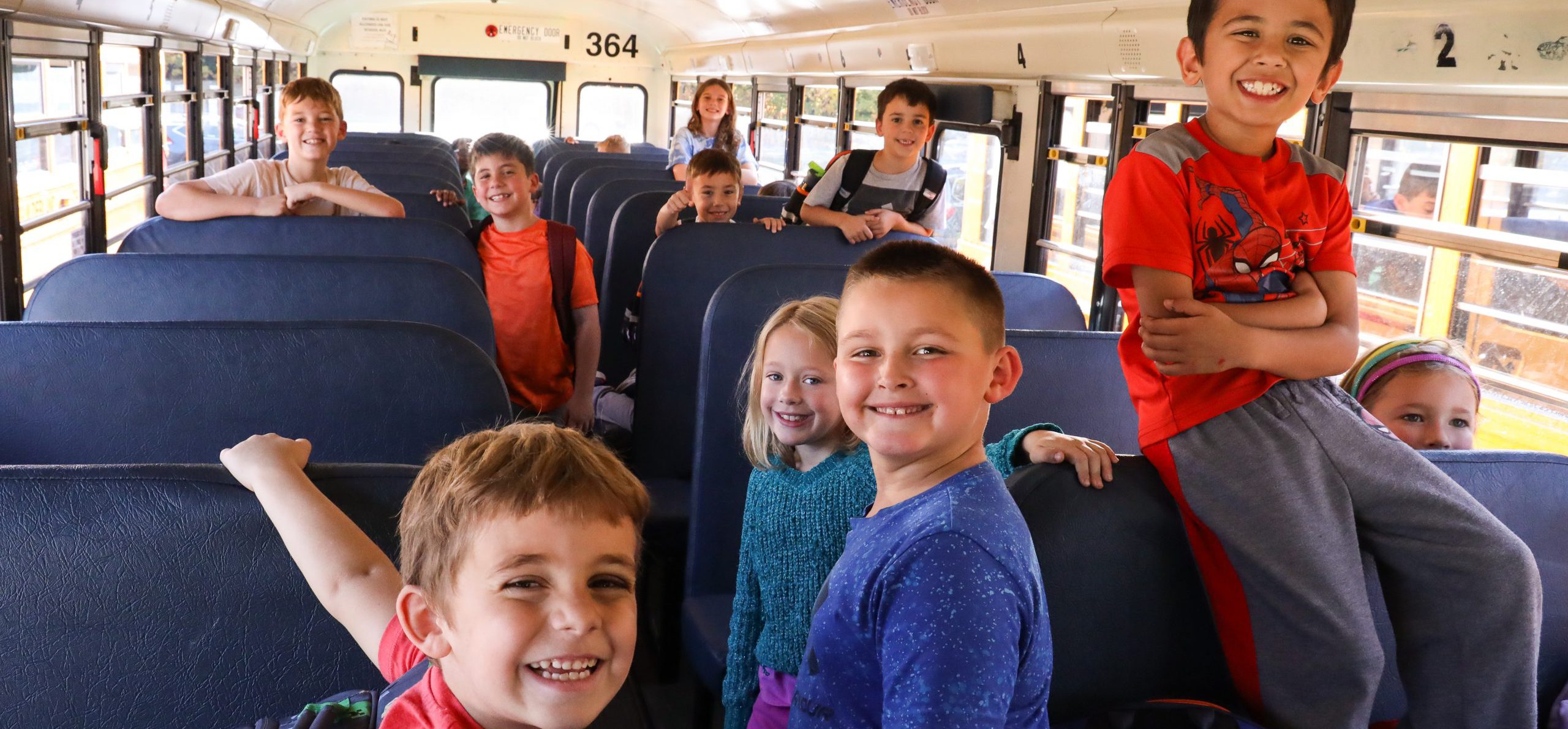 Students smiling on the bus at the end of the day.