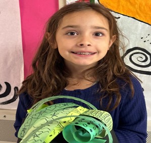 Young student smiling and holding artwork