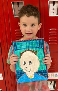 Young student holding artwork.