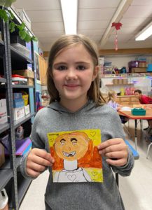 Young student holding up artwork. 