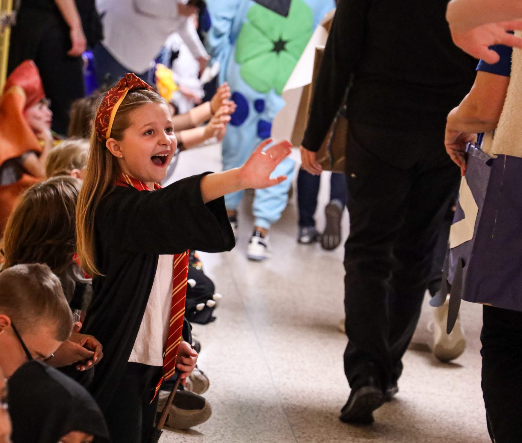 Student smiling and waving. Student is wearing a costume and waving to other students walking in the Halloween Parade.