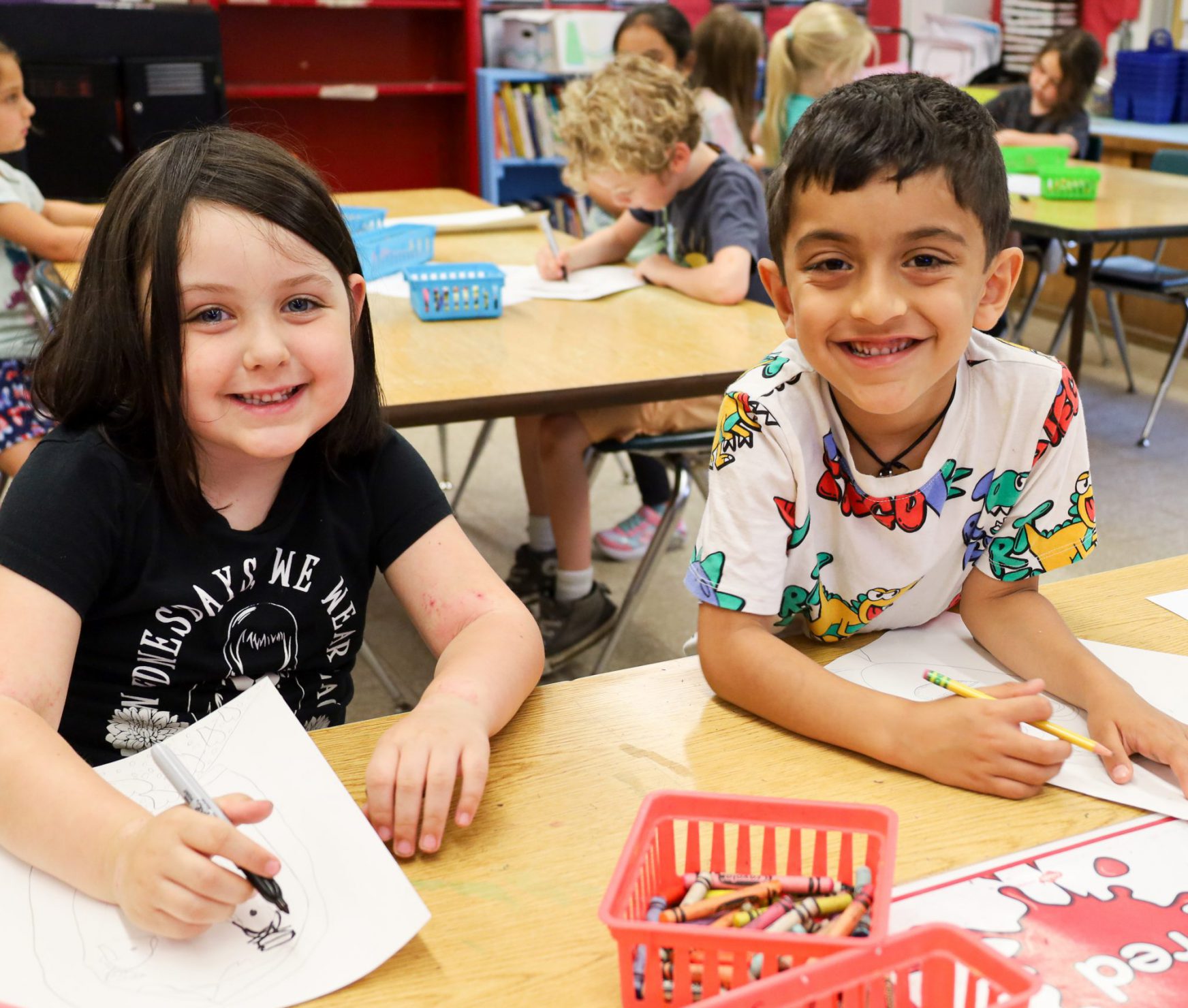 Two elementary students smiling in art class. They are posing for the camera.