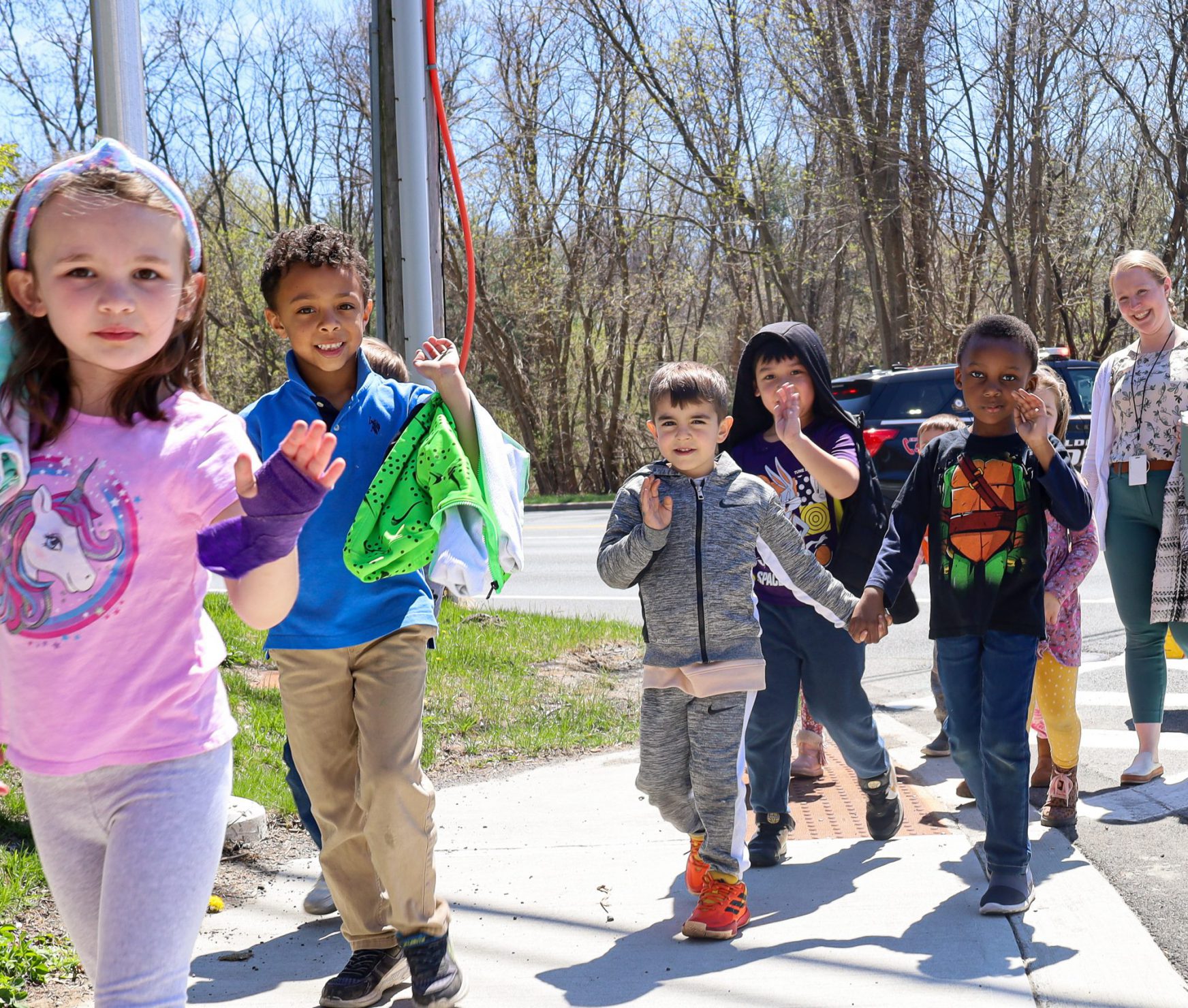 Elementary students and staff walking to school. They are smiling at the camera.