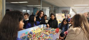 A group of students are gathered around a model of a city as one points out features