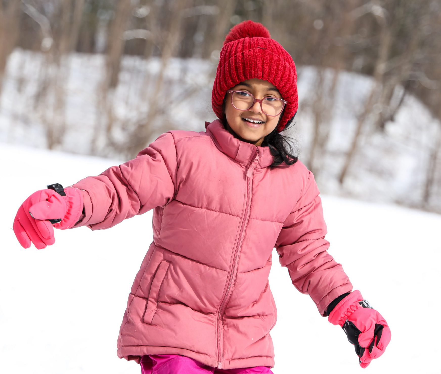 Young student playing in the snow during recess and smiling.