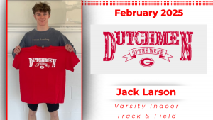 A student stands in front of a white wall, holding a red t-shirt with white lettering that reads "Dutchmen of the Week."