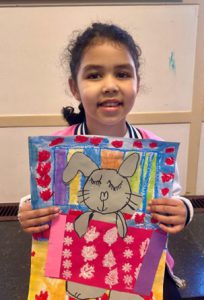 A student holds a piece of colorful artwork